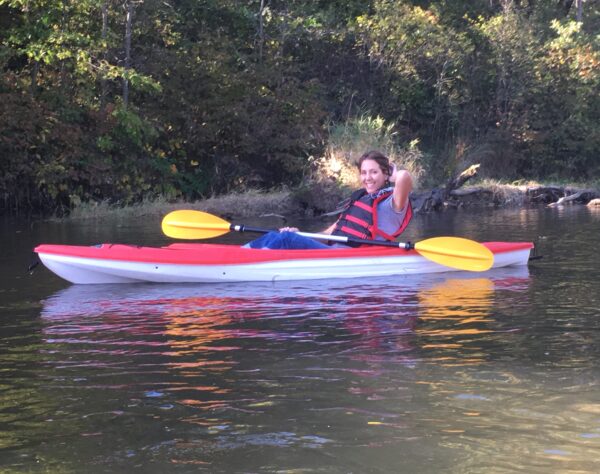 Andrea Jorgenson, Wild Rivers Conservancy Board member, smiling and sitting in a kayak with a paddle on the St. Croix River.