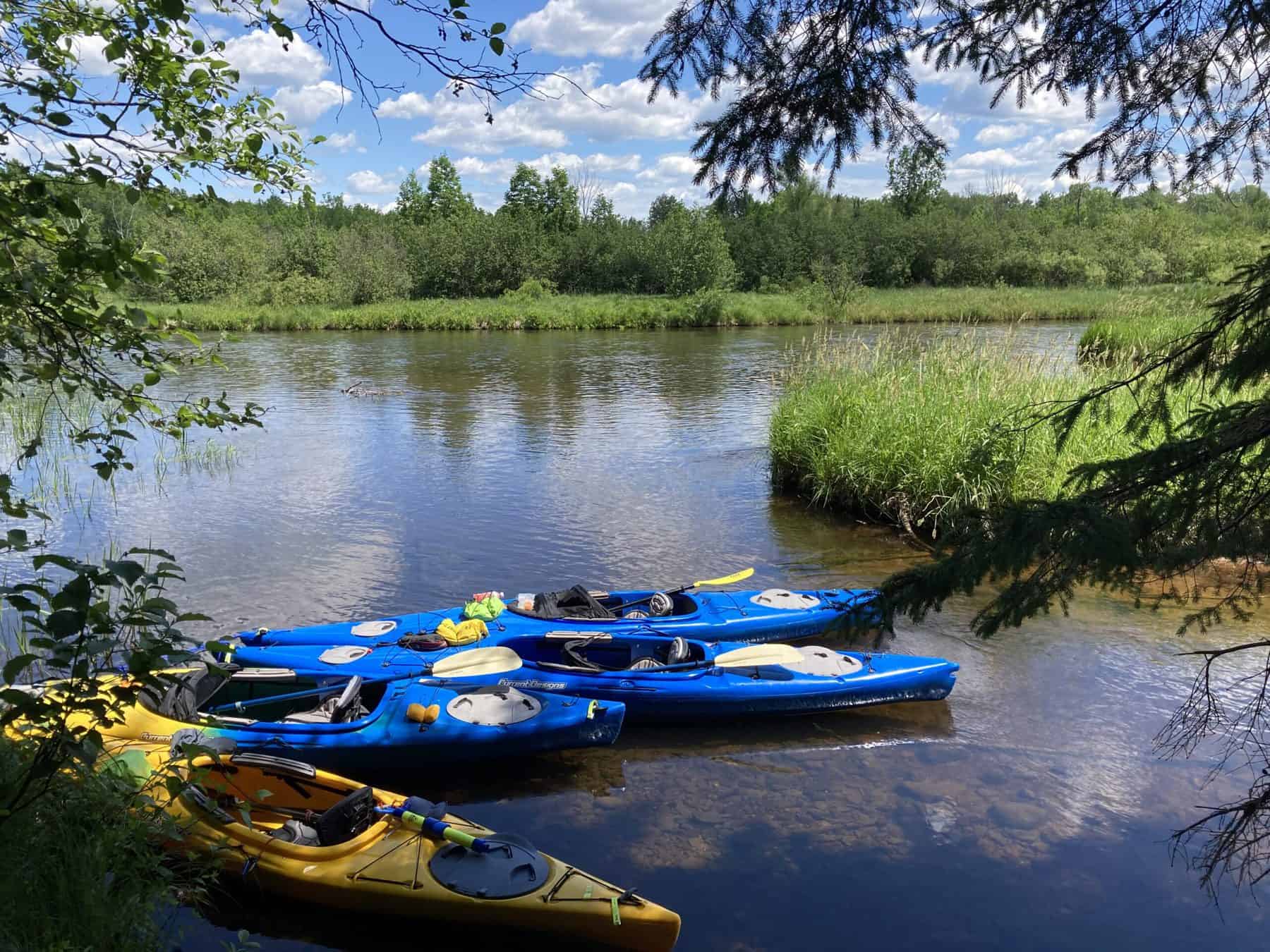Kayaks on the riverbank of the Namekagon on a sunny dat with blue skies. Photo: conservancy Paddle Participant