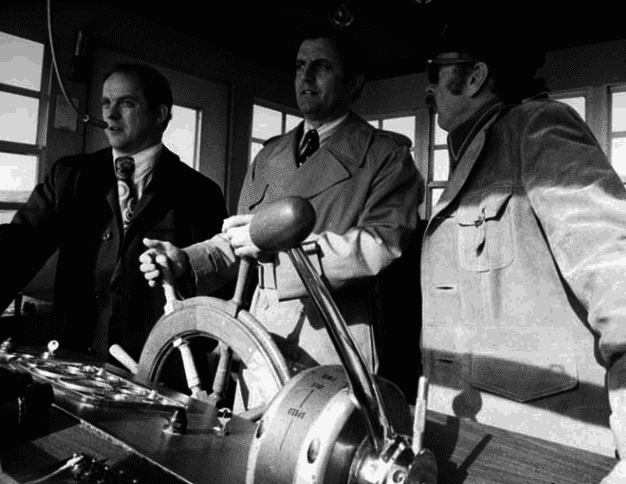 During a tour of the St. Croix River, Senator Walter Mondale takes the helm of a paddlewheeler as Boundary Area Director James Harrison (left) and Captain Bill Bowell (right) look on; credit: Minnesota Historical Society