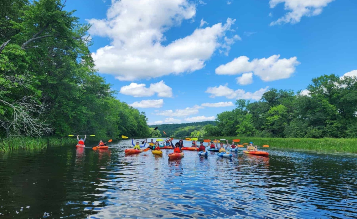 A group of kayakers poses for a photo in the center of the river