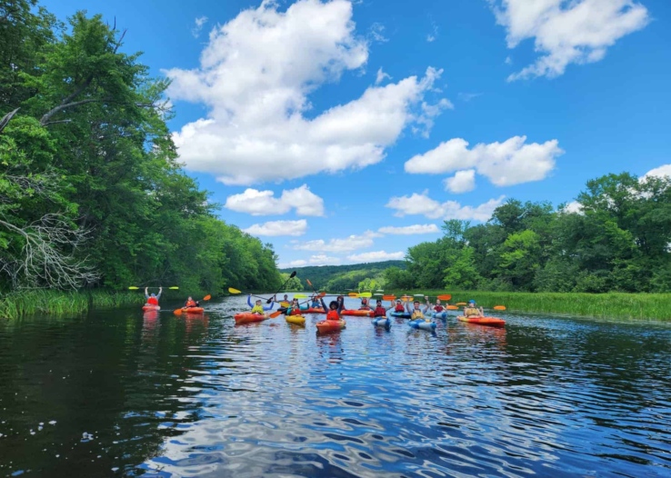 A group of kayakers poses for a photo in the center of the river