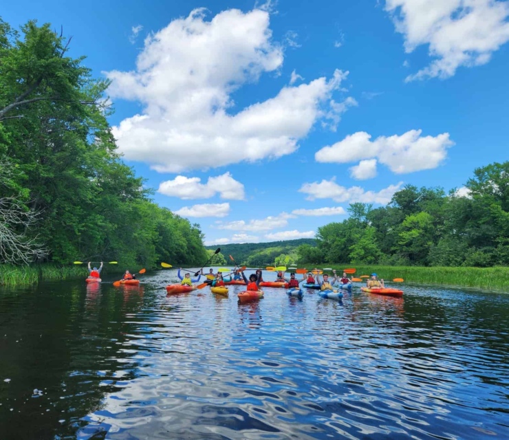 A group of kayakers poses for a photo in the center of the river