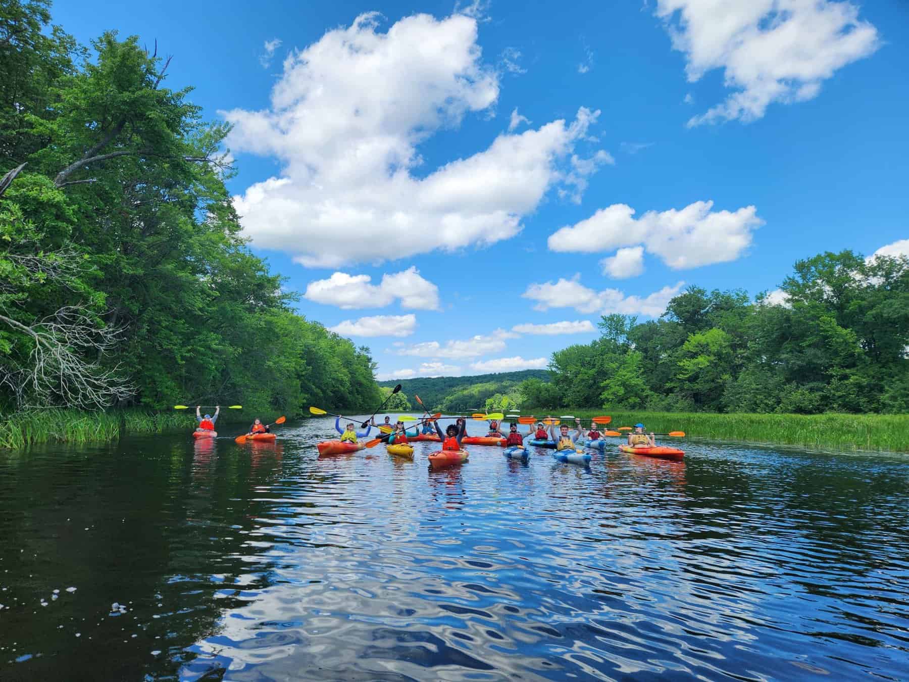 A group of kayakers poses for a photo in the center of the river