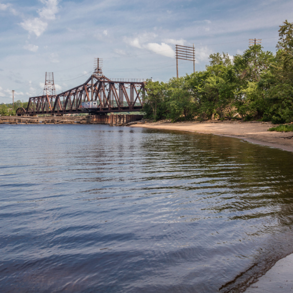 A photoof the lower St. Croix River shows a rusted railraod bridge, and sandy river banks