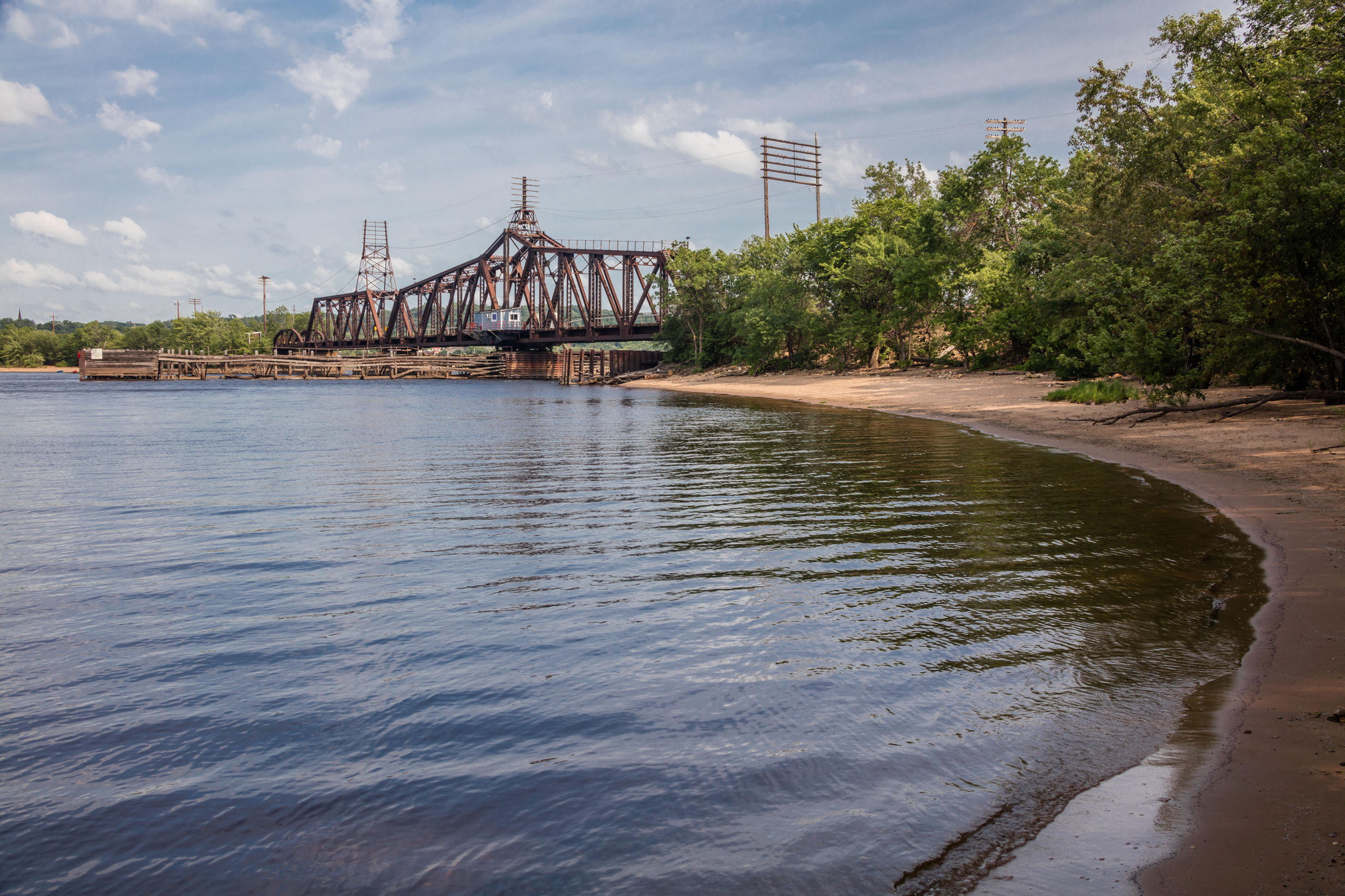 A photoof the lower St. Croix River shows a rusted railraod bridge, and sandy river banks