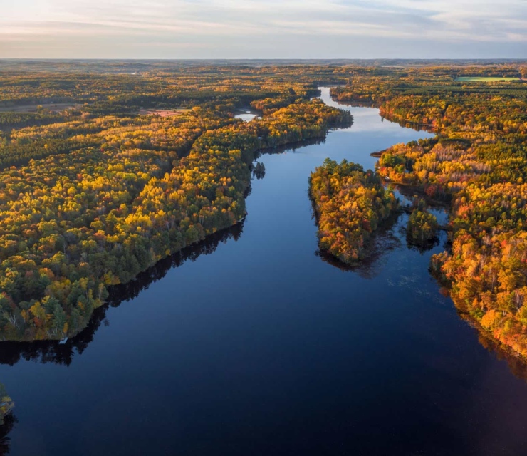 The Namekagon River stretches inth the distance as a blue ribbon. The colors of autumn trees are lit up by the sun.