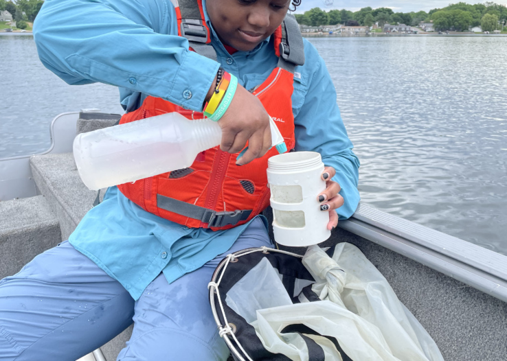 Wild Rivers Conservancy Summer Intern Ajoi takes a water sample from a boat