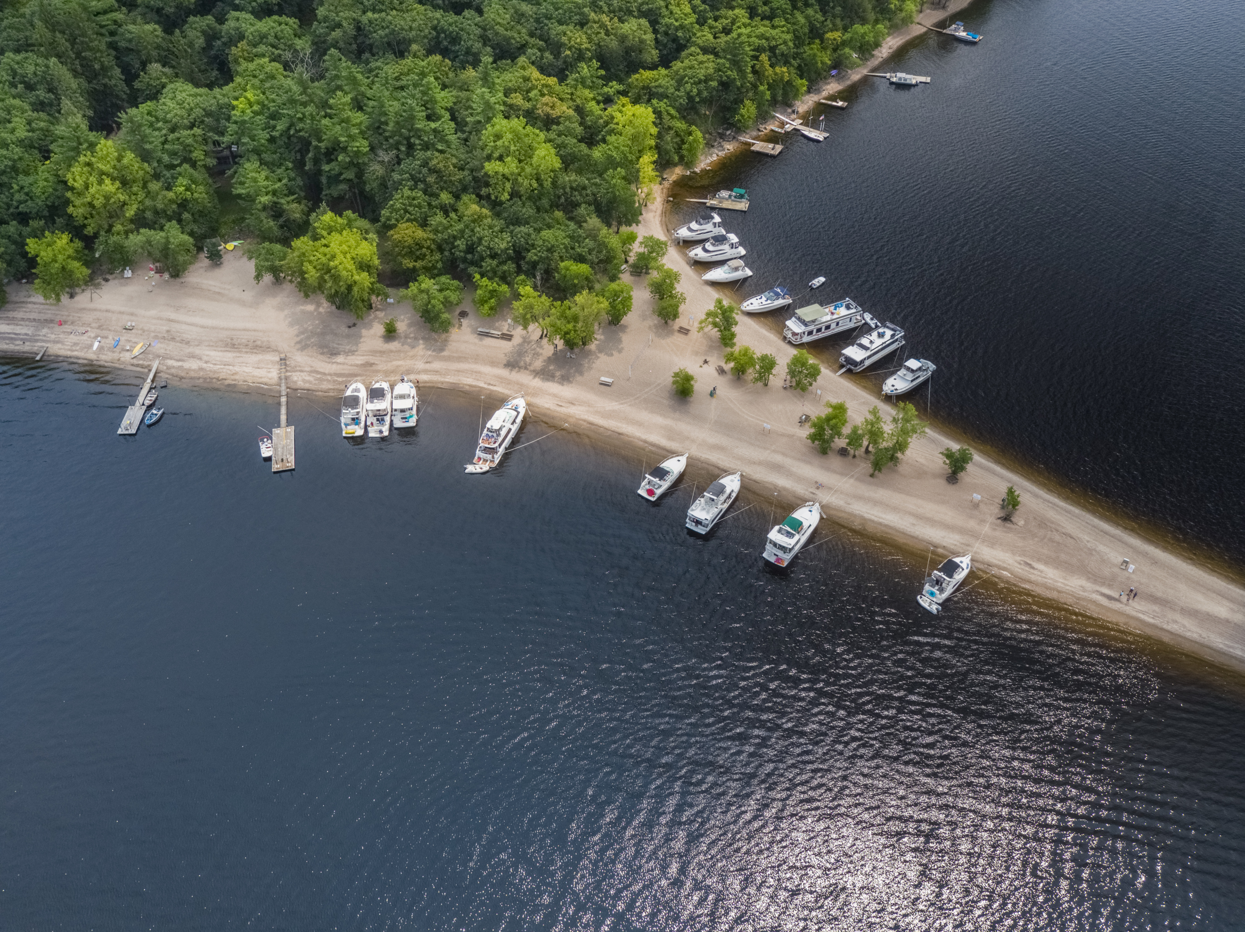 An arial shot shows a collection of boats parked on a sandy point in the St. Croix River.