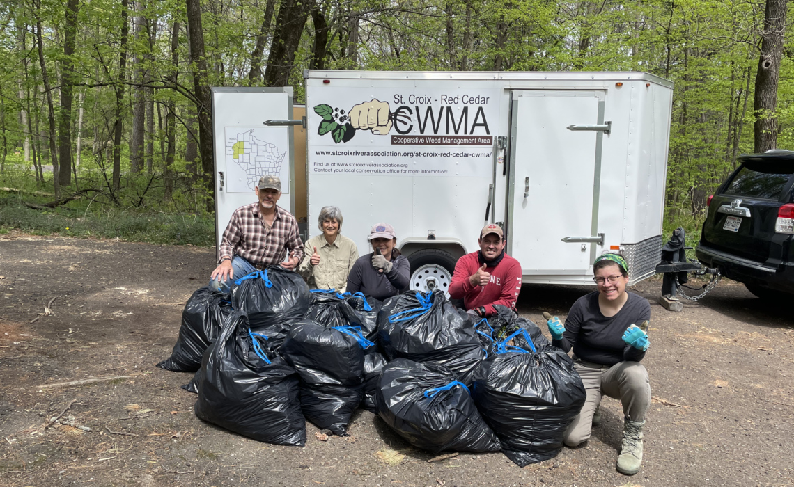 A volunteer group poses in front of the CWMA rental trailer after a day of clearing garlic mustard