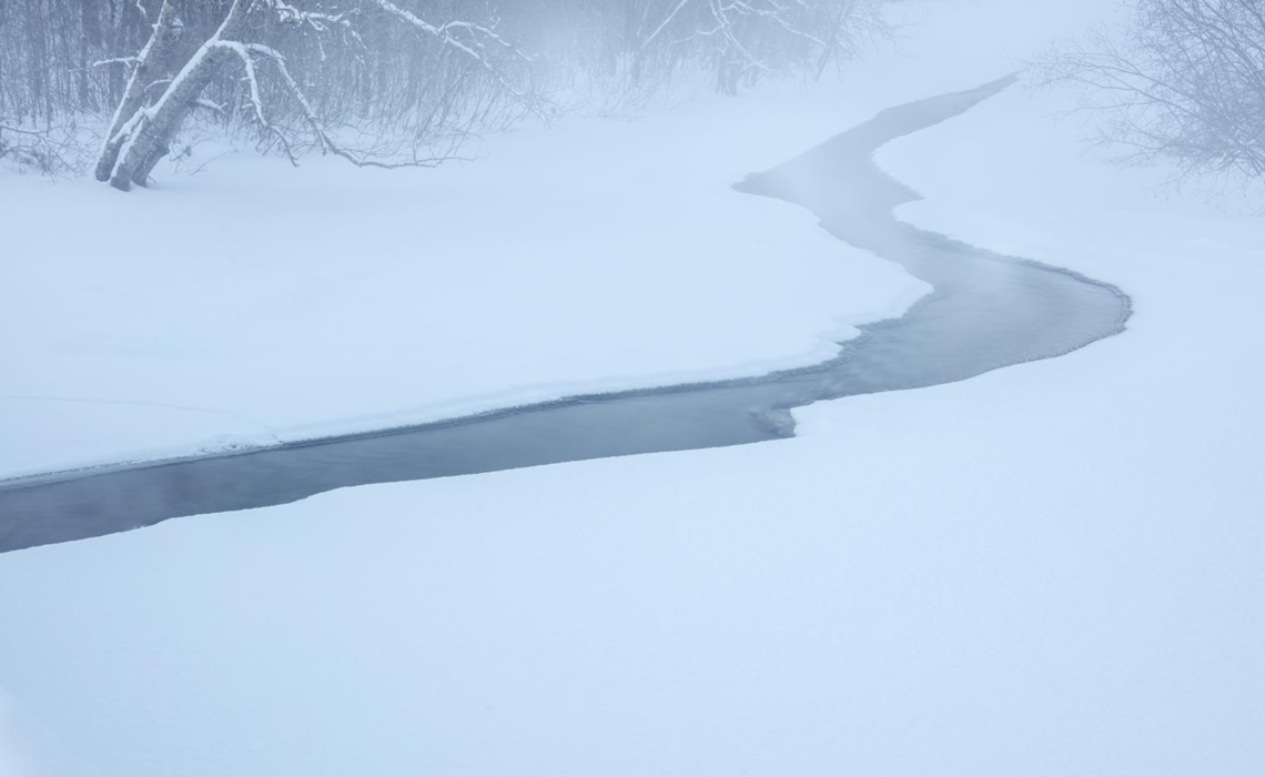 A thin ribbon of water shows between, a frozen section of wriver.
