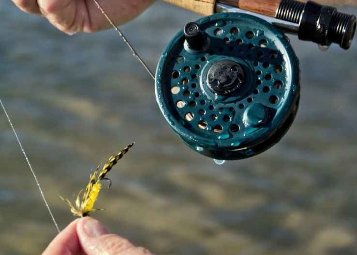 Close up on a fly fishing reel and fly