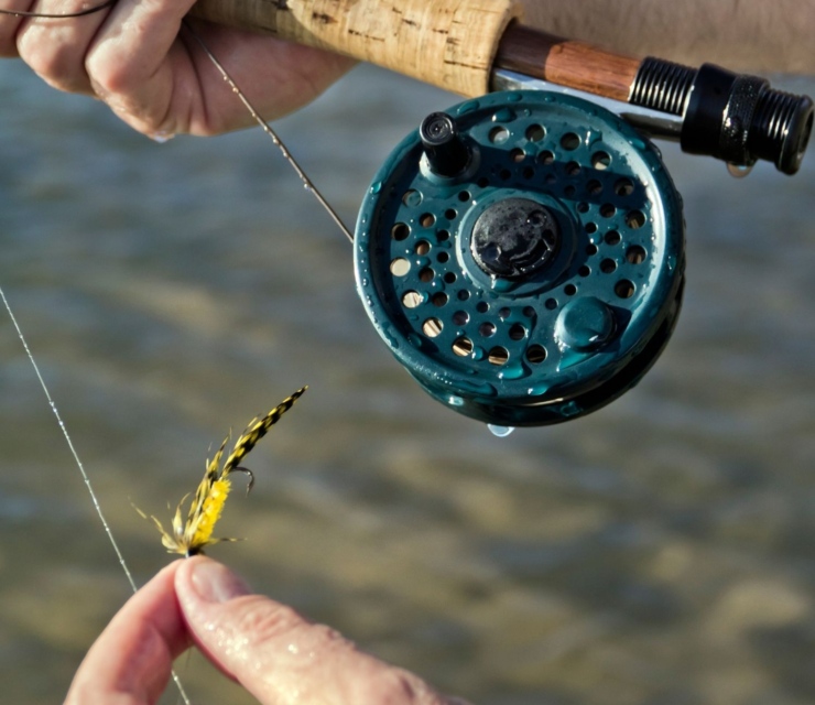 Close up on a fly fishing reel and fly